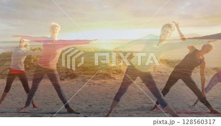 Image of glowing light over portrait of happy senior women exercising by seaside 128560317
