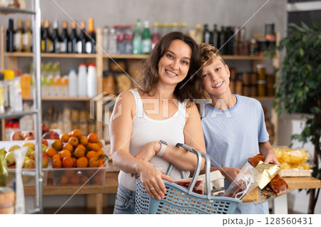 Adolescence boy with mother choose consider snacks in shop 128560431