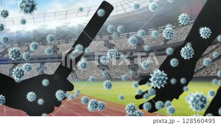 Covid-19 cells floating against silhouette of hand passing a baton against sports stadium Covid-19 cells floating against silhouette of hand passing a baton against sports stadium 128560495