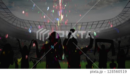 Colorful confetti falling over silhouette of fans cheering and sports stadium in background 128560519