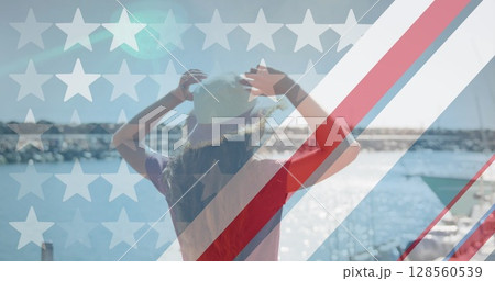 American flag design pattern and multiple stars against rear view of woman standing on a wooden pier 128560539