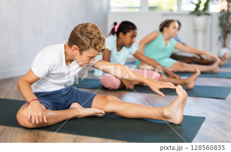 Boy stretches and prepares to perform Jana Shirshasana Boy stretches and prepares to perform Jana Shirshasana 128560835