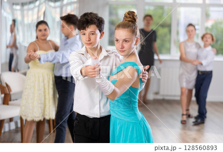 Adolescent ballroom dancers practicing elegant dance moves in pairs Adolescent ballroom dancers practicing elegant dance moves in pairs 128560893