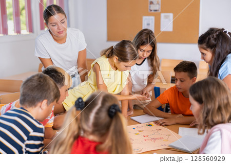 Kids and female teacher playing together educational board game in classroom at school 128560929