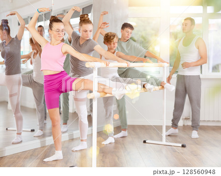 Ballet pose grand batman - girls and boys at a choreography lesson are learning ballet movements in studio 128560948
