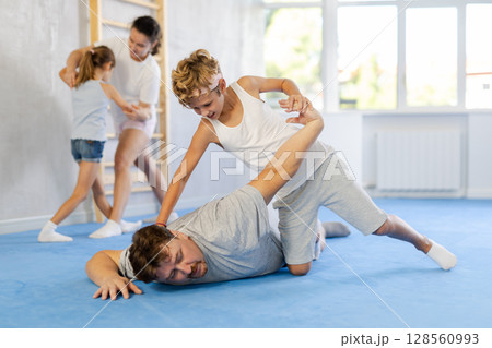Tween boy practicing self defense skills in training bout with father Tween boy practicing self defense skills in training bout with father 128560993