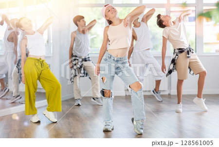 Girl in baseball cap with two hair pigtails with group of teenage friends, learn to dance hip hop Girl in baseball cap with two hair pigtails with group of teenage friends, learn to dance hip hop 128561005