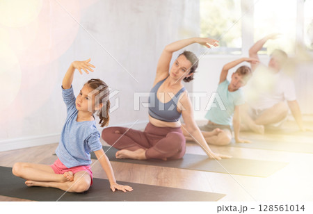 Mother and family performing yoga exercises at yoga studio, family health concept 128561014