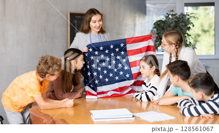 Teacher talks about the country and the national flag of United States of America in a geography lesson. Teenage students listen carefully Teacher talks about the country and the national flag of United States of America in a geography lesson. Teenage students listen carefully 128561067