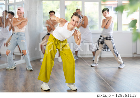 Group of sporty teenagers practicing hip hop dance in training hall during dancing classes 128561115