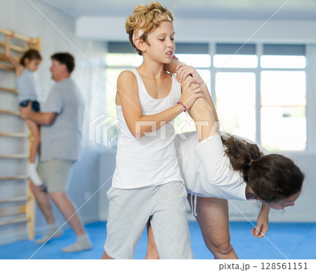 Preteen boy practicing self-defense techniques in sparring with mother Preteen boy practicing self-defense techniques in sparring with mother 128561151