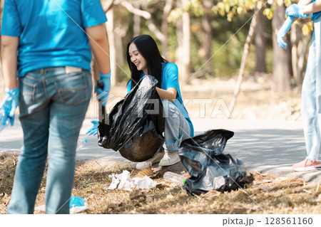 Young Volunteers Cleaning Up Park Litter on a Sunny Day, Engaging in Community Service and Environmental Conservation 128561160