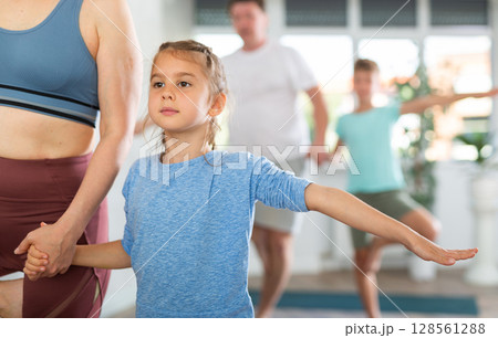 Sweet little girl practicing tree pose in pair with her mother Sweet little girl practicing tree pose in pair with her mother 128561288