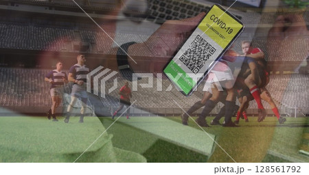 Image of man holding smartphone with covid 19 vaccination passport over american football player Image of man holding smartphone with covid 19 vaccination passport over american football player 128561792