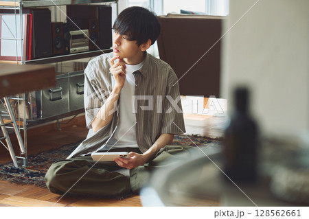 部屋で思案する男性 128562661