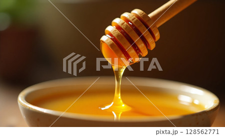Golden Honey Dripping from Dipper into Rustic Bowl Macro Golden Honey Dripping from Dipper into Rustic Bowl Macro 128562771