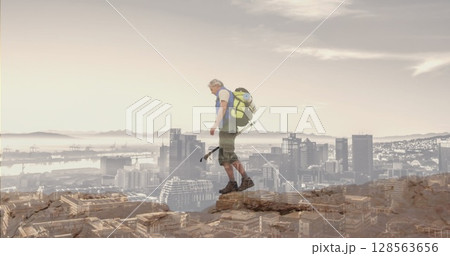 Composite of caucasian senior man hiking on mountain, and modern cityscape Composite of caucasian senior man hiking on mountain, and modern cityscape 128563656