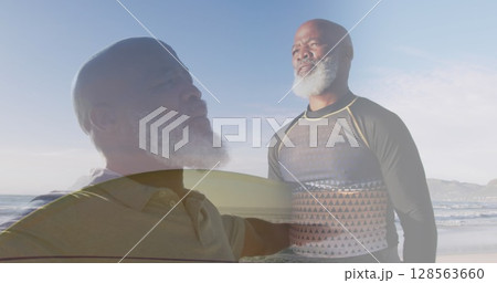 Composite of african american senior man stretching arms, and carrying surfboard on sunny beach 128563660