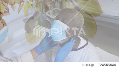 Composite of doctor and senior african american male patient in face mask, and leaves in sun Composite of doctor and senior african american male patient in face mask, and leaves in sun 128563680