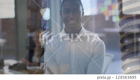 Composite of portrait of happy african american man in office, and city buildings 128563695