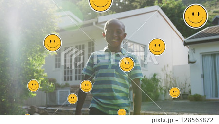 Image of smiley faces over happy african american boy in garden Image of smiley faces over happy african american boy in garden 128563872