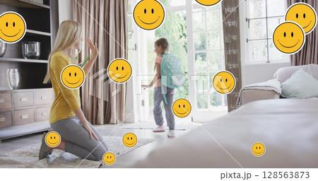 Image of smiley faces over happy caucasian mother preparing daughter for school 128563873