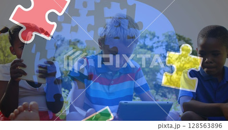 Image of colourful puzzle pieces and human head over children using tablets 128563896