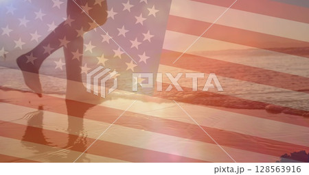 Image of flag of united states of america over woman walking on beach 128563916