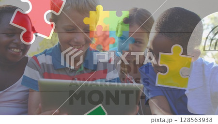 Image of colourful puzzle pieces and autism text over children using tablet 128563938