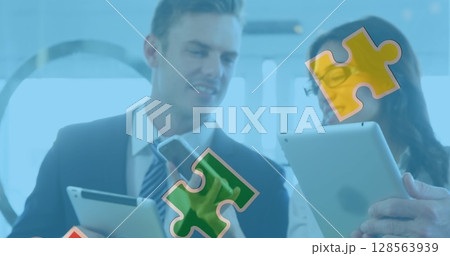 Image of colourful puzzle pieces over business people using digital devices 128563939