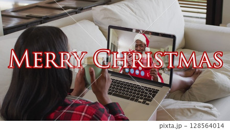 Image of merry christmas text over caucasian woman on laptop image call with her family 128564014