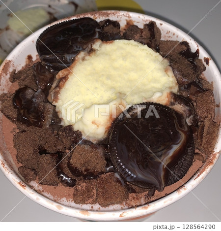 Rich and indulgent chocolate bingsu topped with chocolate syrup, brownie chunks, and chocolate shavings. A heavenly treat for chocoholics seeking a cool and creamy dessert escape. 128564290