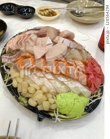 Fresh and delicate sashimi slices, beautifully presented with vibrant colors and perfect cuts. This traditional Japanese delicacy highlights the pure flavors of premium seafood. 128564294