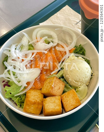 A vibrant poke bowl filled with fresh, marinated fish, rice, and colorful toppings like avocado, seaweed, and sesame seeds. A healthy, satisfying meal with rich textures and flavors. 128564301