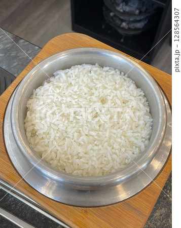 Steaming bowl of fluffy white rice, freshly cooked to perfection. Its delicate aroma and tender texture make it an ideal base for a variety of savory dishes. 128564307