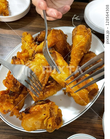 Crispy Korean fried chicken, perfectly glazed with a sweet and spicy sauce. Ideal for food photography and menus, showcasing the irresistible crunch and flavor of this beloved dish. 128564308