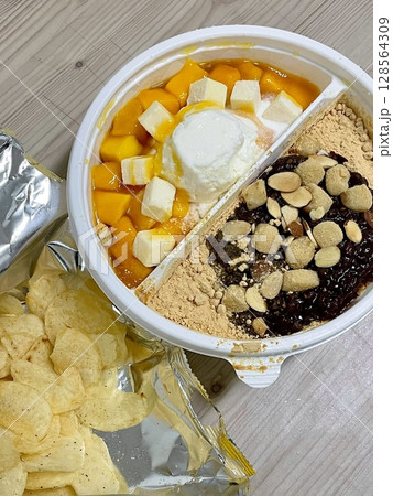 A refreshing bowl of bingsu, topped with fluffy shaved ice, vibrant fruits, and sweet toppings. Perfect for summer treats, this Korean dessert captures the essence of indulgence and delight. 128564309