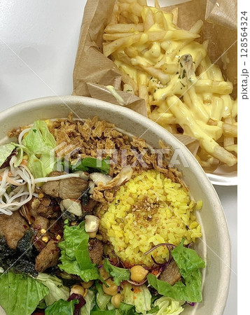 Colorful poke bowl with fresh fish, veggies, and rice served alongside crispy golden French fries an unexpected yet delicious fusion of clean, healthy bites and indulgent crunch. Colorful poke bowl with fresh fish, veggies, and rice served alongside crispy golden French fries an unexpected yet delicious fusion of clean, healthy bites and indulgent crunch. 128564324