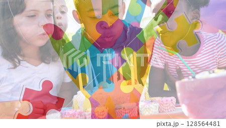 Image of colourful puzzle pieces hand over children with birthday cake at party 128564481