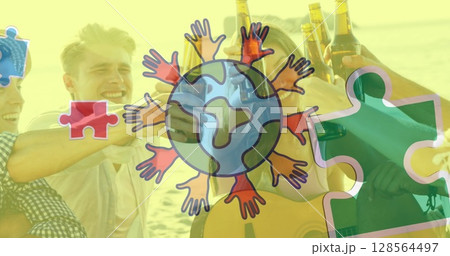 Image of colourful puzzle pieces and globe with hands over happy friends at summer beach party 128564497