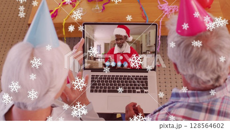 Image of snow falling text over senior caucasian couple on laptop image call at christmas Image of snow falling text over senior caucasian couple on laptop image call at christmas 128564602