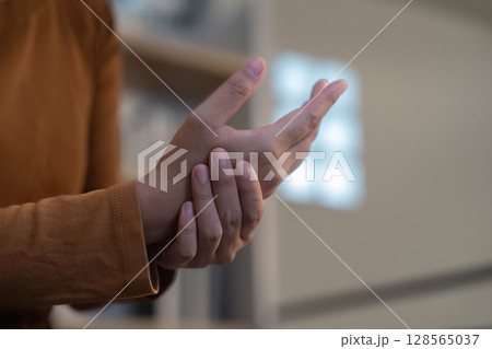Wrist Pain Relief. Individual holding wrist, experiencing discomfort. Wrist Pain Relief. Individual holding wrist, experiencing discomfort. 128565037