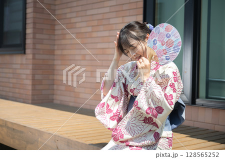 頭をおさえる浴衣女性 128565252