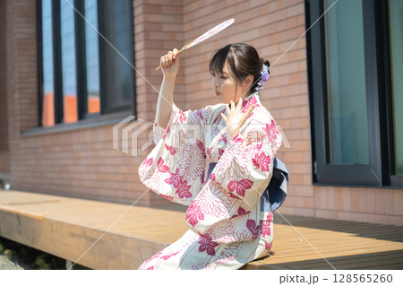 うちわで日を遮る浴衣女性 128565260