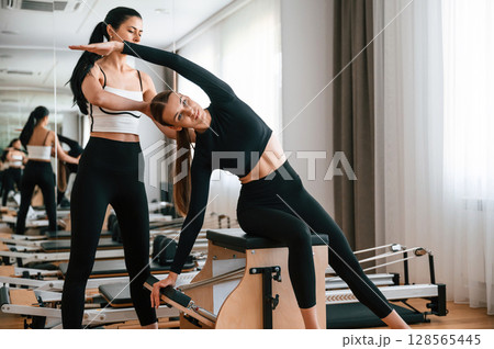 Teaching how to stretch spine. Women in fitness center are doing exercises 128565445