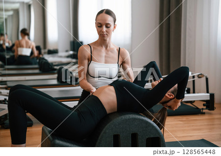Personal trainer is controlling the process. Women in fitness center are doing exercises Personal trainer is controlling the process. Women in fitness center are doing exercises 128565448