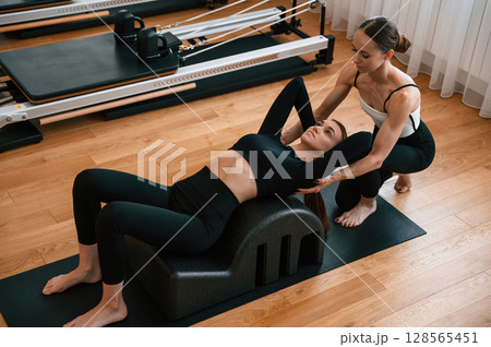 Personal trainer is controlling the process. Women in fitness center are doing exercises Personal trainer is controlling the process. Women in fitness center are doing exercises 128565451
