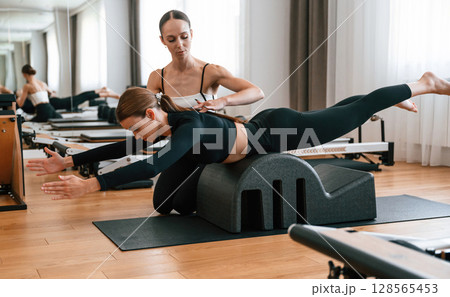 Trainer is helping with exercises. Women in fitness center 128565453