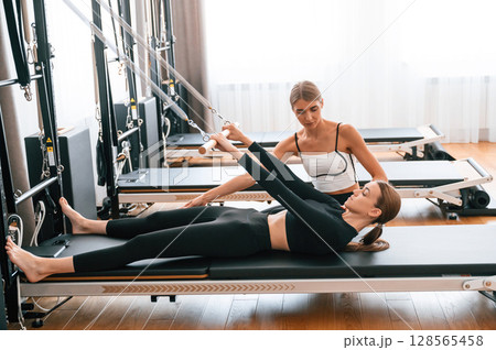 Trainer is helping with exercises. Women in fitness center Trainer is helping with exercises. Women in fitness center 128565458