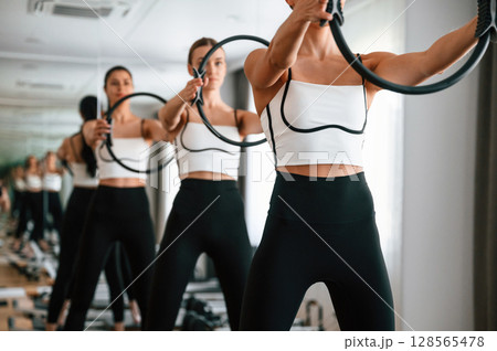 Three women in fitness center are doing exercises 128565478